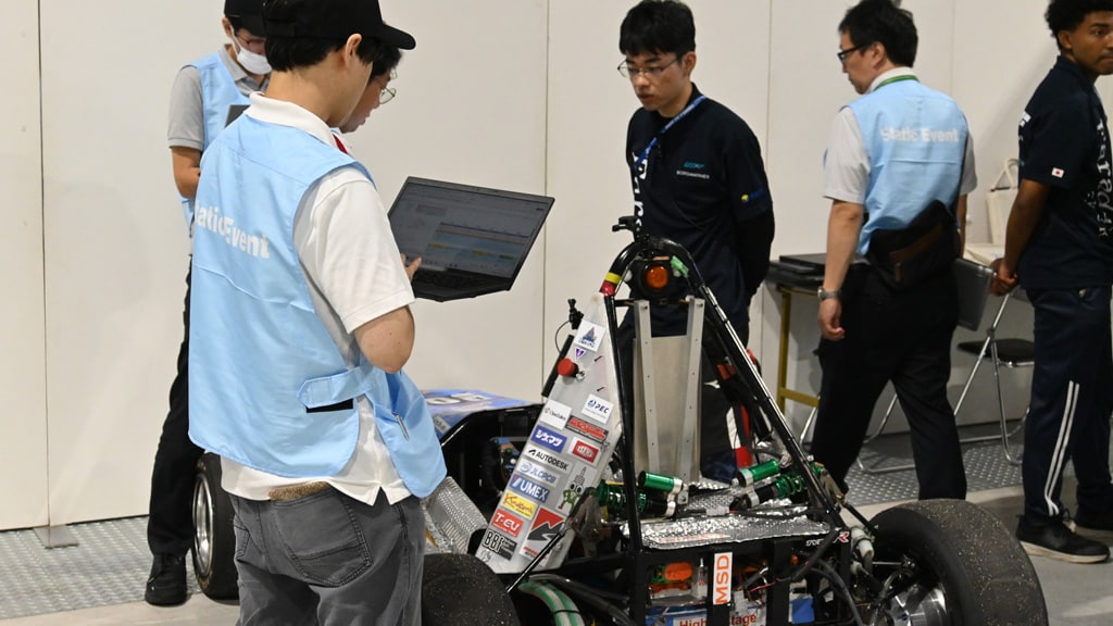 これは東京大学の学生フォーミュラチーム (UTFF) がコスト審査を受けている写真です。